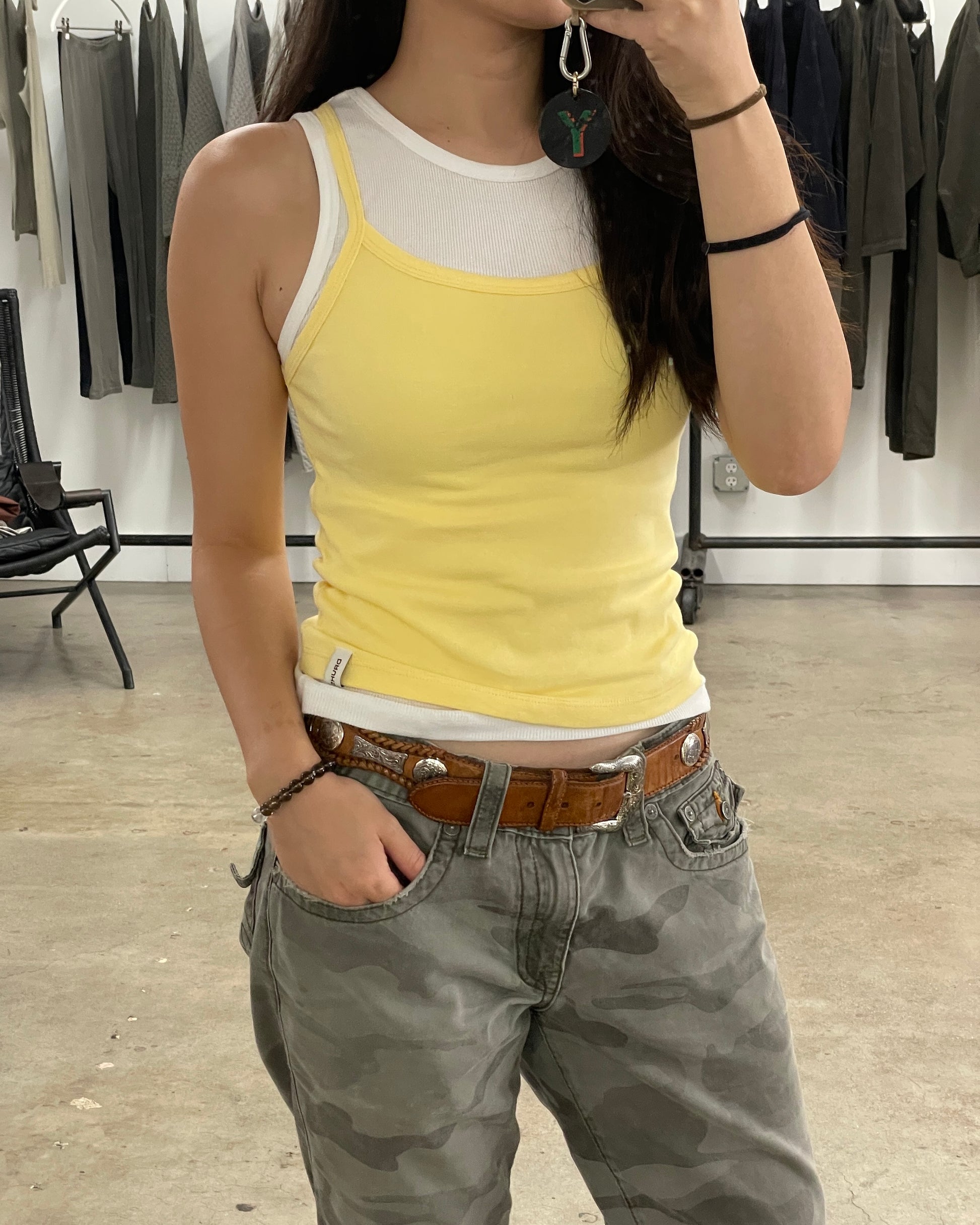 Person wearing a yellow tank top and camouflage pants in a clothing store.